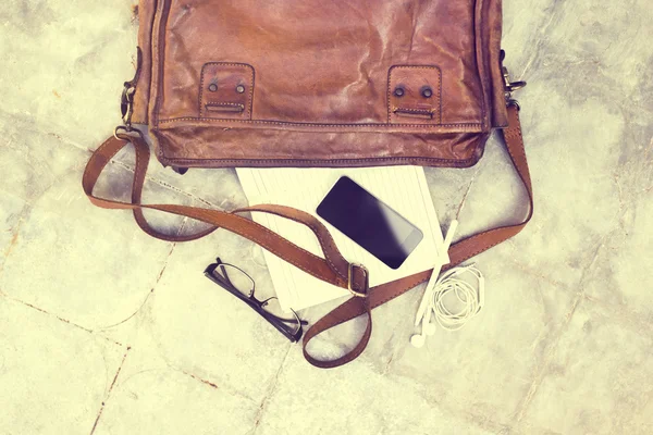 Leather bag with blank diary, cell phone, headphones and glasses