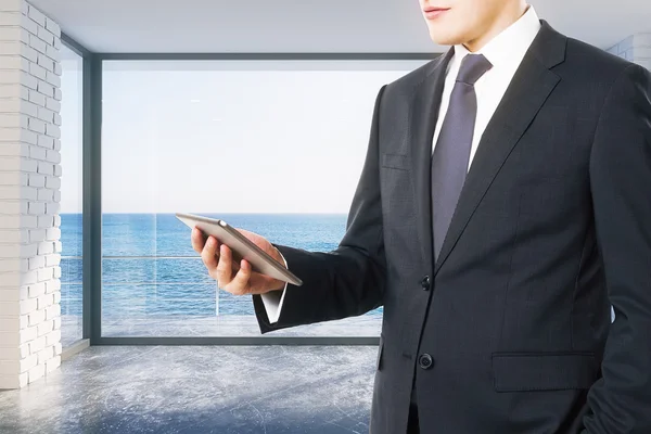 Businessman looking at digital tablet in empty loft room with oc