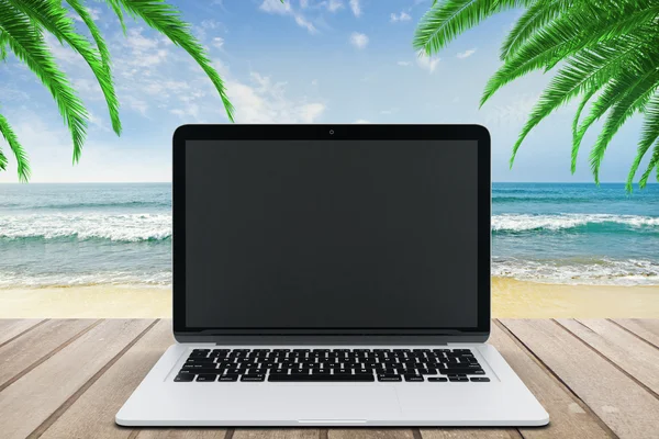 Blank black laptop screen on wooden bench on the beach, mock up