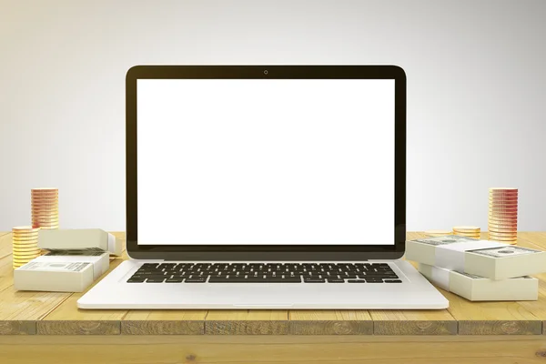 Blank laptop on a wooden table with a wad of cash and gold coins