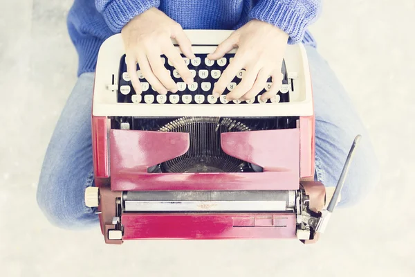 Top view of a woman sitting on the floor and typing typewriter