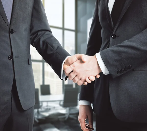Two businessman shaking hands standing in the office