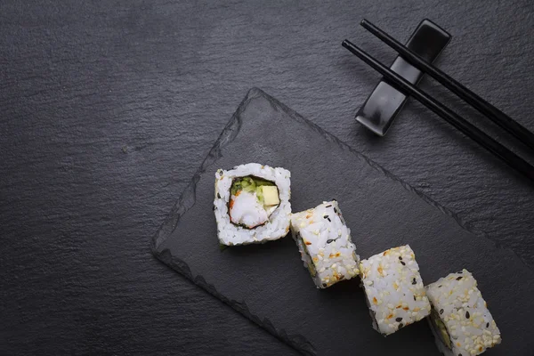 Sushi roll on a stone plate over black background