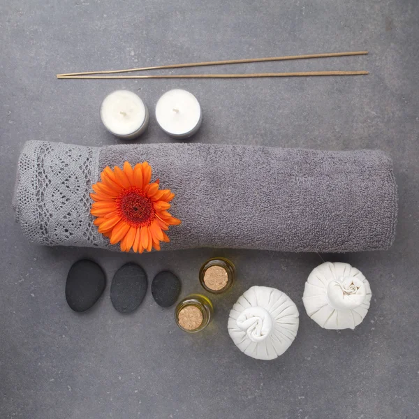 SPA still life with towels, candles, massage balls and gerbera flowers on a grey surface. Flat lay. Top view