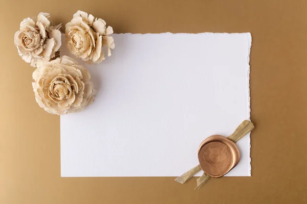 Letter with wax seal and dry roses on golden background. Flat lay. Top view