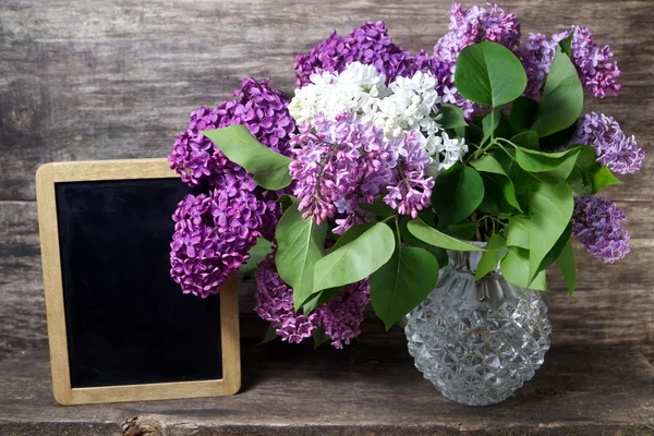 Lilac flowers in a vase and blackboard