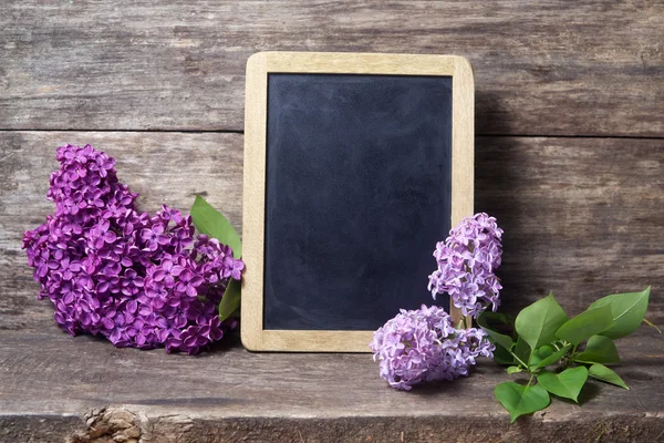 Lilac flowers in a vase and blackboard