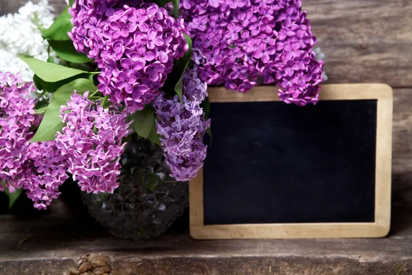 Lilac flowers in a vase and blackboard