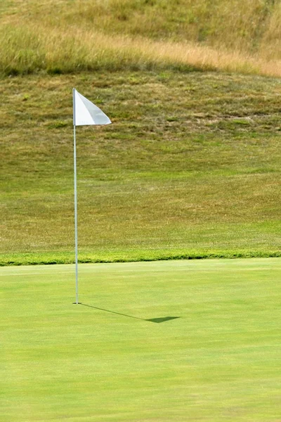 Nice golf course on a sunny summer day. Hole with a flag. Popular outdoor sport.