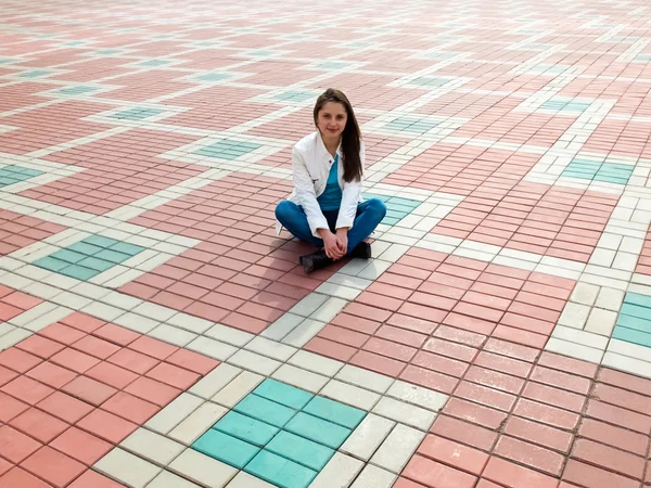 Photo of woman sitting on the paving slab