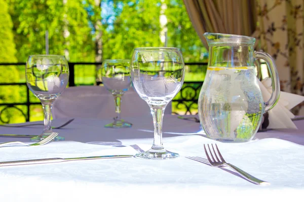 Table with glasses and white tablecloth in bower