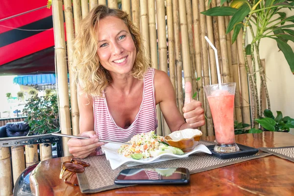 Young tourist woman eating fried rice and drinking fruit smoothie at thai restaurant in Phuket Thailand - Gastronomy concept with happy person traveler tasting local asian food - Happy smiling girl