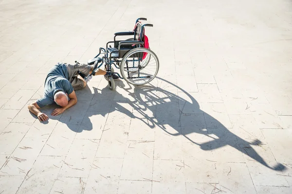 Disabled man with handicap having an accident crash with wheelchair - Disability concept with powerless unhelped person lying on the floor - Social issues with invalid guy on difficultes