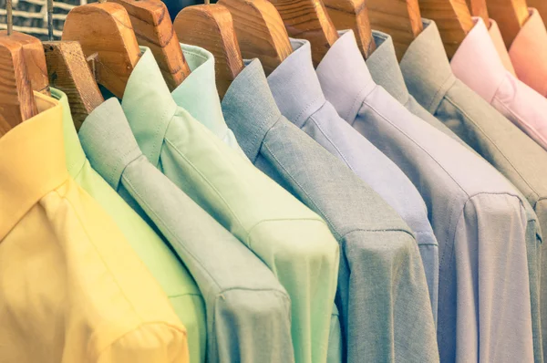 Multicolored shirts hanging on shop rack at weekly flea market - Elegant wardrobe sale concept and alternative retro colors fashion styling - Soft vintage filtered look - Shallow depth of field