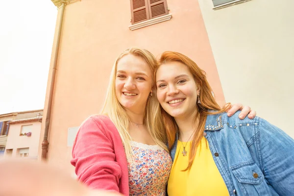 Young women girlfriends taking selfie at old town - Travel concept with happy girls having fun together - Best female friends catching moment with modern smartphone - Warm saturated rose quartz filter