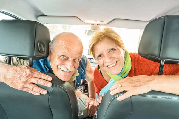 Happy senior couple ready for driving car on journey trip - Concept of joyful active elderly with retired man and woman enjoying their best years - Modern mature travel lifestyle during retirement