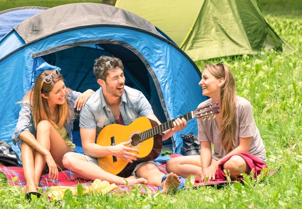 Group of best friends singing and having fun camping together - Concept of carefree youth and freedom outdoors in the nature - Caucasian young people during vacations