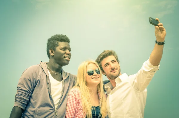 Group of multiracial happy best friends taking a selfie outdoors - International concept of happiness and multi ethnic friendship all together against racism for peace and fun - Vintage filtered look