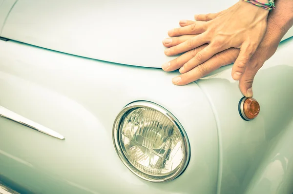 Couple of lovers holding hands on a vintage classic car body - Concept of love and connection with vintage lifestyle and travel trasportation - Retro nostalgic filtered look
