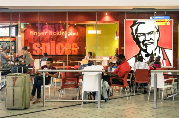 JOHANNESBURG, SOUTH AFRICA - NOVEMBER 28, 2014: melting pot people at KFC restaurant in Tambo International Airport. Kentucky Fried Chicken is a world famous fast food restaurant chain