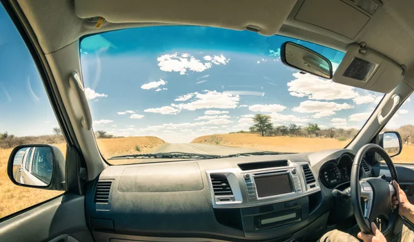 Travel landscape from a car cockpit - Concept of adventure trip on the road to exlcusive destinations - Fisheye view on desert street and cloudscape during world tour in Namibia african excursion