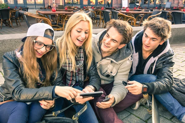 Group of young hipster friends having fun together with smartphone - Modern situation of technology interaction in everyday lifestyle - Internet wifi connection spots outdoors