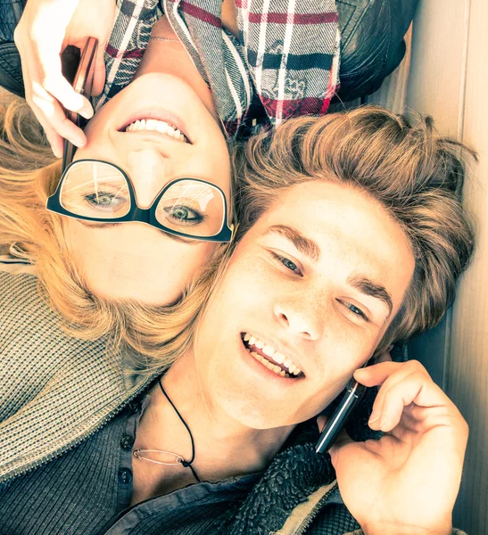 Couple in love having fun with smartphones - Close up of happy hipster lovers - Youth concept with new trends and technologies - Warm saturated vintage filtered look inspiring the upcoming spring