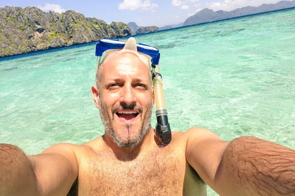 Handsome man taking a selfie during islands hopping at El Nido in Palawan - Boat trip snorkeling in exotic scenarios - Adventure travel lifestyle around Philippines - Composition with tilted horizon