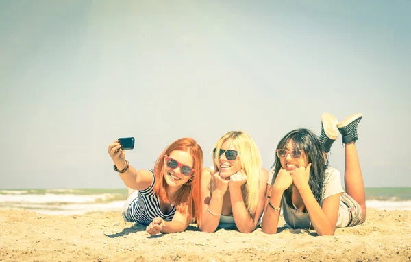 Happy girlfriends taking a selfie at beach - Concept of friendship and fun in the summer with new trends and technology - Best friends enjoying moments with modern smartphone - Vintage filtered look