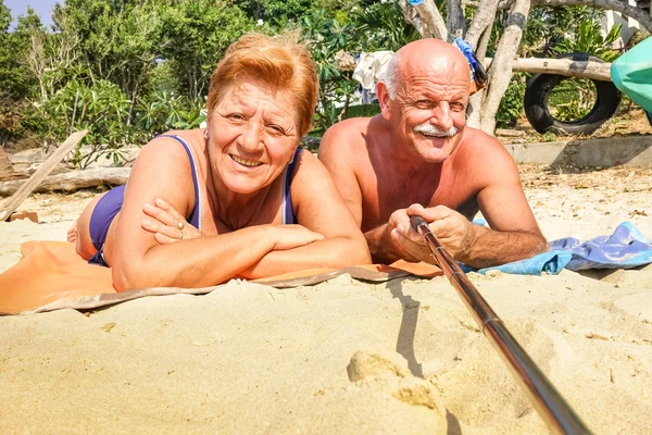 Senior happy couple taking selfie with stick in Thailand trip - Adventure concept of active elderly and fun around the world - Hot sunny day with real saturated light conditions