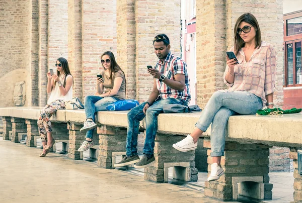 Group of young multiracial friends using smartphone with mutual disinterest towards each other - Technology addiction in actual lifestyle - Soft vintage filtered look with main focus on male person