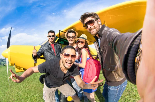 Best friends taking selfie at aeroclub with ultra light airplane - Happy friendship fun concept with young people and new technology trend - Sunny afternoon vivid color tones - Fisheye lens distortion