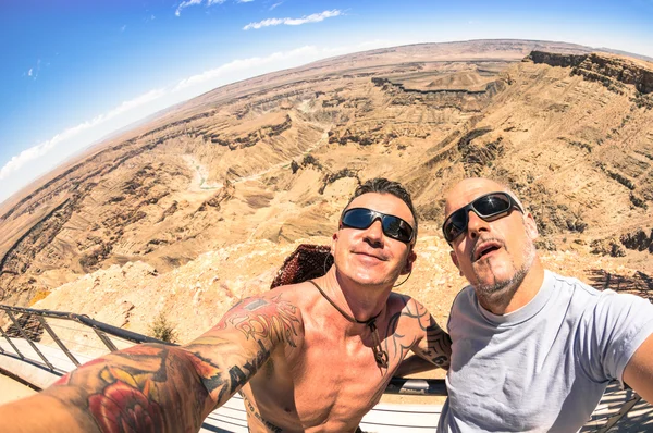 Adventurous best friends taking selfie at Fish River Canyon in Namibia - Adventure travel lifestyle enjoying happy fun moment - Trip together around the world beauties - Fisheye horizon distortion