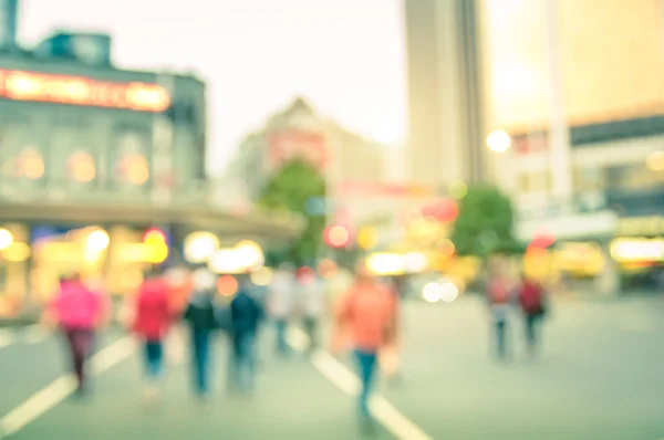 Blurred defocused background of people walking on the road with vintage multicolored filter - Abstract bokeh of crowded Queen Street in Auckland city center during rush hour in urban business area