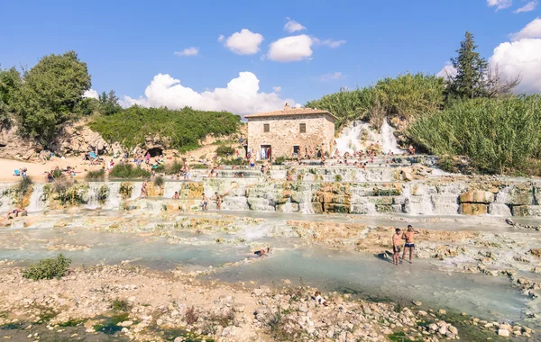 SATURNIA, ITALY - SEPTEMBER 24, 2015: international tourists swimming and relaxing in world famous hot springs in Saturnia at Mulino natural waterfalls by Manciano municipality in tuscan Maremma