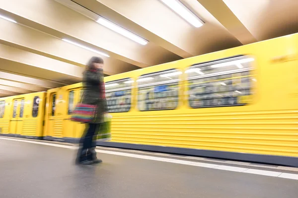 Defocused person standing in front speeding train - Underground transportation concept with blurred vehicle moving in subway - Generic metro public transport and unrecognizable woman with autumn wear