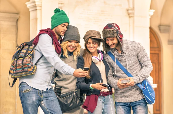 Group of young hipster tourists friends having fun with smartphone in the old town - Traveling lifestyle concept with happy people connected with new trendy technologies - Warm autumn filtered look