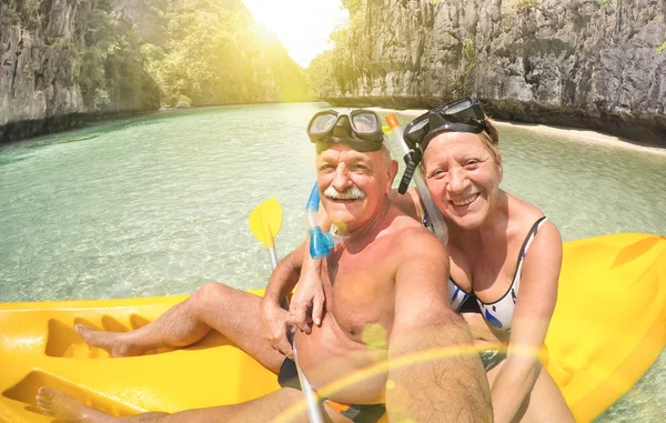 Senior happy couple taking selfie on kayak at Big Lagoon in El Nido Palawan - Travel to Philippines wonders - Active elderly concept around the world - Lens flare and sun halo are part of composition