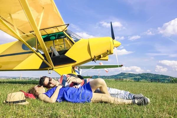 Relaxed couple of lovers having a rest during charter airplane excursion - Wanderlust concept of alternative people lifestyle traveling around the world - Love and fun watching pictures on smartphone