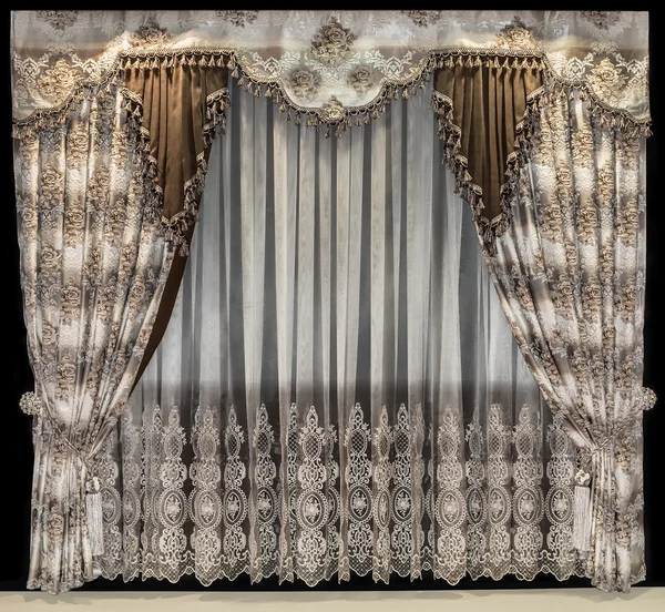 Luxurious interior design. Bilateral curtains with floral pattern. Delicate tulle and a pelmet with fringed