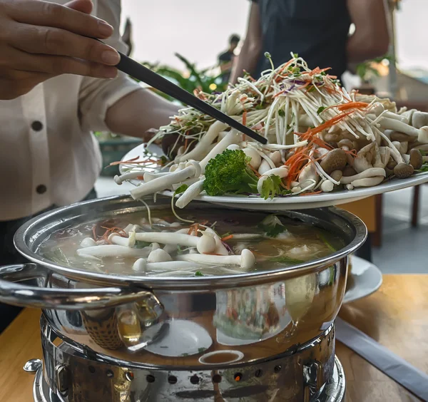 Cooking Vietnamese, Asian dishes in a cafe and restaurant on the dining table. Mushrooms and seafood cooked in a big pan in the fire.