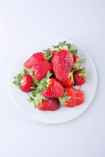 Strawberry red on a white plate and a white background, a bright image with contrast. side view, top. summer red berries. a series of color photographs