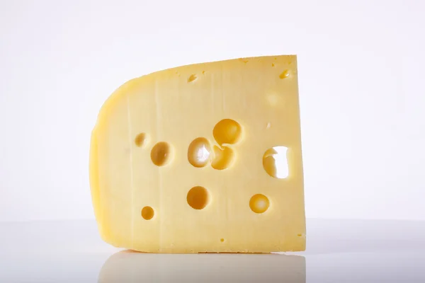 Milk product. piece  cheese with big holes.a piece of cheese with the large holes on a light background with a gradient. alpinland.