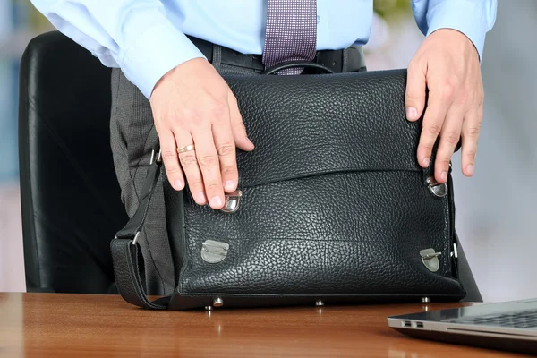 Businessman  standing closing  a  leather briefcase.