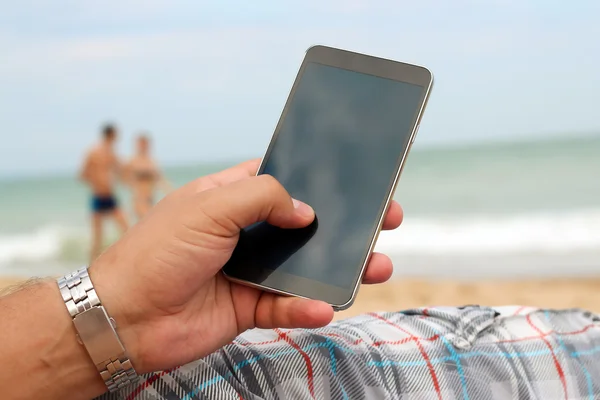 Man holding a mobile phone. internet connection on the beach. Sea behind