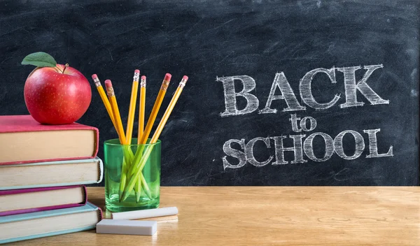 Back to school - apple on books with pencils and blackboard