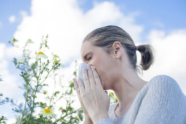 Woman sneezing in a daisy flowers meadow