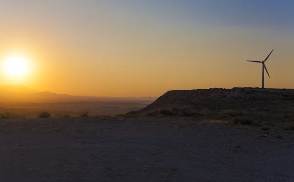 Electric wind turbines farm with sunset light on arid landscape