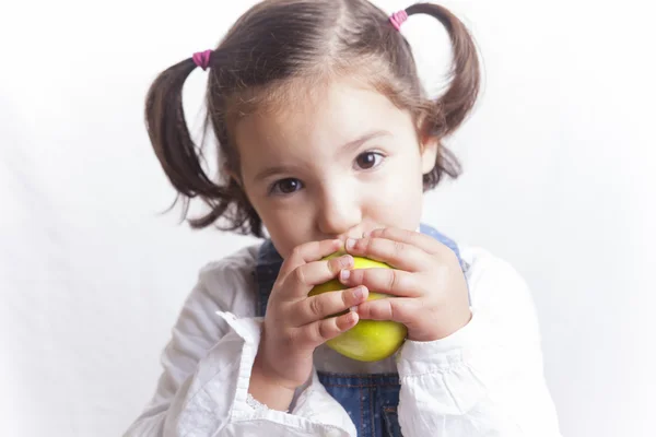 Little girl biting a green apple