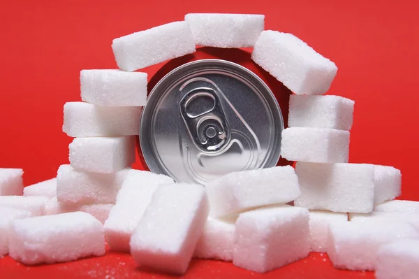 Cola refreshing drink can and lot of white sugar cubes representing the big amount of calories